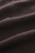 Nahaufnahme des dunkelbraunen B.F. Knitwear Merino V-Neck Pullovers im feinen Strickbild, gedreht aus schräger Perspektive.