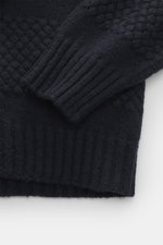 Nahaufnahme des Ärmels und Saums des 04651/ A trip in a bag V-Neck Pullover 'Light Wool' navy, fotografiert von oben, mit feinem Strickbild, Strukturstrick an Saum und Ärmeln, breiten Rippbündchen, weichem Griff, Regular Fit, V-Ausschnitt und Mix aus Woll