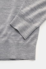Nahaufnahme des von Braun Merino Feinstrick V-Neck Pullovers hellgrau aus reiner Merinowolle, Regular Fit, V-Ausschnitt, flexible Rippbündchen, weicher Griff, feines Strickbild, leichte Qualität, fotografiert von oben auf Ärmel und Saum.
