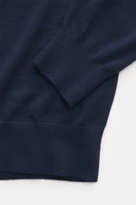 Nahaufnahme des von Braun Merino Feinstrick V-Neck Pullovers navy, mit Fokus auf flexible Rippbündchen, feines Strickbild und weichen Griff, fotografiert von schräg oben.