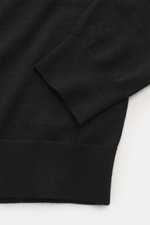 Nahaufnahme eines von Braun Merino Feinstrick V-Neck Pullovers schwarz, fotografiert von oben auf Bündchen und feines Strickbild aus reiner Merinowolle.