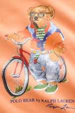 Nahaufnahme des Polo Ralph Lauren Kapuzenpullover hellorange mit Polo-Bear-Print auf dem Vorderteil, fotografiert aus frontaler Perspektive.