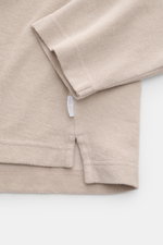Close-up view of the beige 04651/ A trip in a bag Terry hooded jumper 'Terry' showing sleeve, hem, and side seam with woven label. 

<p>Comfort and coolness with summery nonchalance: The hooded jumper 'Terry' by 04651/ A TRIP IN A BAG made of pure cotton 