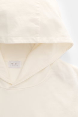 04651/ A trip in a bag Kapuzenpullover 'IF Hoodie' creme, Detailansicht der Kapuze aus gebürstetem Jersey mit weichem Griff und kleinem Weblabel, von oben fotografiert.