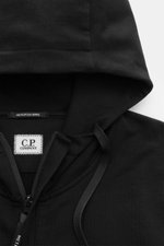 Nahaufnahme der Kapuze der C.P. Company Sweatjacke schwarz aus elastischem Baumwoll-Stretch-Fleece, mit Tunnelzug und robustem Reißverschluss.