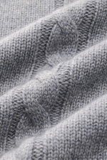 Nahaufnahme des von Braun Cashmere Rollkragenpullovers grau, fotografiert aus schräger Perspektive, zeigt weichen Links- und Zopfstrick.