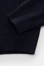 Nahaufnahme des von Braun Cashmere Mock Neck Pullovers navy, seitlich fotografiert, mit mittelfeinem Strukturstrick, Rippbündchen und weichem Griff aus reinem mongolischem Cashmere.