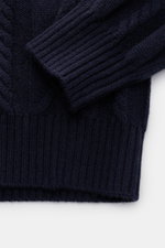 Close-up of the sleeve and bottom hem of the von Braun Cashmere turtleneck jumper navy, photographed from above, showing its premium pure cashmere, very soft feel, medium-fine knit, timeless cable knit pattern, slim fit, close-fitting turtleneck, and flex