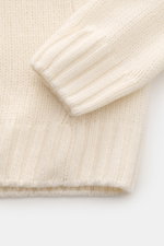 Nahaufnahme des 04651/ A trip in a bag Cashmere Rollkragenpullovers creme, von oben fotografiert, grobes Strickbild, weiche Rippsäume, Oversized Fit.