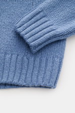 Close-up view of the sleeve and hem of the 04651/ A trip in a bag Cashmere Rollkragenpullover rauchblau, showing its soft, coarse knit, ribbed cuffs, and oversized fit.  
<p>Essenziell für kühle Tage: Der Rollkragenpullover aus der 'Look of the Games' Ca