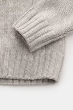 Close-up front view of 04651/ A trip in a bag Cashmere Rollkragenpullover hellgrau meliert, showing soft, coarse knit, ribbed cuffs, and turtleneck collar. Essenziell für kühle Tage: Der Rollkragenpullover aus der 'Look of the Games' Capsule von 04651/ A 