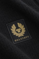 Nahaufnahme des schwarzen Belstaff Rollkragenpullover 'Watch' mit grobem Strickbild, weichem Griff, Rippstrick-Elementen, Slim Fit, Rollkragen, flexible Rippbündchen und BELSTAFF-Weblabel auf der Brust.