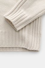 Nahaufnahme des Belstaff Rollkragenpullover 'Watch' creme, fotografiert von oben, mit grobem Strickbild, reiner Wolle, weichem Griff, Rippstrick-Elementen, Slim Fit, Rollkragen, BELSTAFF-Weblabel auf der Brust und flexiblen Rippbündchen.