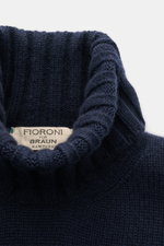 Close-up top-down view of the navy Fioroni Cashmere Rundhalspullover showcasing its ribbed turtleneck and label. <p>Souveräne Eleganz in ihrer luxuriösesten Form: Der Rollkragenpullover von FIORONI aus erlesenem Cashmere vereint meisterhafte italienische 