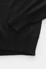 Close-up from above of the sleeve and hem of the Fioroni Cashmere turtleneck sweater 'Duvet' black, showing pure cashmere, fine knit pattern, ribbed turtleneck, slim fit, and flexible ribbed cuffs with a very soft feel.