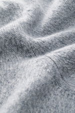 Nahaufnahme des Fedeli Cashmere Rollkragenpullovers 'Derby Saddler' grau meliert aus feinem, weichem Strick mit flexiblem Rippbündchen, fotografiert in Detail-Perspektive.