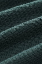 B.F. Knitwear Merino turtleneck jumper dark green close-up from above, showing pure merino wool, soft feel, semi chunky knit, slim fit, ribbed turtleneck, flexible ribbed bands.