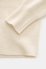 Close-up top-down view of B.F. Knitwear Cashmere Turtleneck Sweater cream showing soft pure cashmere, medium-fine knit, slim fit, fitted turtleneck, and elastic rib-knit cuffs.