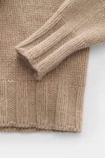 Close-up, top-down view of the B.F. Knitwear Cashmere turtleneck sweater beige melange sleeve and knit texture, showing soft, coarse knit with elastic ribbed cuffs.

Description for context:
<p>Autumnal cashmere from the knitting expert B.F. KNITWEAR: Thi