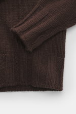 Close-up top-down view of the dark brown B.F. Knitwear Cashmere turtleneck sweater showing its coarse knit texture and elastic ribbed cuffs.