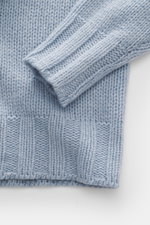 Close-up from above of the sleeve and lower body of the B.F. Knitwear Cashmere turtleneck sweater light blue melange showing coarse knit texture and elastic ribbed cuffs.

<p>Autumnal cashmere from the knitting expert B.F. KNITWEAR: This softly knitted tu