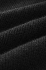 Close-up, angled view of black B.F. Knitwear Cashmere turtleneck sweater showing coarse knit texture and soft touch fabric.