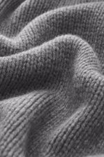 Close-up front perspective of B.F. Knitwear Cashmere turtleneck sweater grey melange showing coarse knit texture, soft touch, and ribbed cuffs. Autumnal cashmere from the knitting expert B.F. KNITWEAR: This softly knitted turtleneck sweater is the perfect