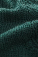 Close-up front view of the B.F. Knitwear Cashmere turtleneck sweater dark green showing coarse knit texture and soft cashmere fibers.