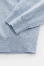 Close-up top-down view of Aida Barni Cashmere turtleneck sweater light blue melange, showing flexible ribbed cuffs, fine knit pattern, and soft pure cashmere fabric, slim fit with close-fitting turtleneck, a warm autumn/winter must-have.