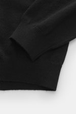 Close-up top-down view of Aida Barni Cashmere turtleneck sweater black, showing pure cashmere fabric, soft feel, fine knit, slim fit, close-fitting turtleneck, and flexible ribbed cuffs. Italian knitwear by AIDA BARNI with a timeless look, perfect for aut