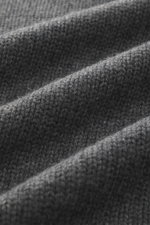 Nahaufnahme des mittelgroben Strickbilds des dunkelgrau melierten Della Ciana Rollkragenpullovers mit weichem Griff, Slim Fit, Rollkragen und komfortablen Rippbündchen, fotografiert aus seitlicher Perspektive, Mix aus Wolle und Cashmere.