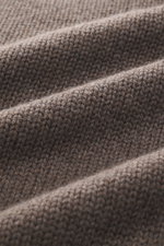Nahaufnahme des Della Ciana Rollkragenpullovers graubraun meliert mit mittelgrobem Strickbild, weichem Griff, Slim Fit, komfortablen Rippbündchen, Rollkragen, Mix aus Wolle und Cashmere, fotografiert aus schräger Perspektive.