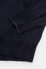Nahaufnahme des navyfarbenen Brunello Cucinelli Feinstrick-Rollkragenpullovers, schräg von oben fotografiert, aus Schurwolle und Cashmere mit feinem Strickbild, Rippstrick-Rollkragen und komfortablen Rippbündchen.