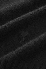 Ami Paris Cashmere Rollkragenpullover schwarz, Detailaufnahme der weichen Cashmere-Wollmischung mit mittelfeinem Strickbild, Logo-Stitching, Rippbündchen, Regular Fit, anliegender Rollkragen, aus Nahaufnahme fotografiert.