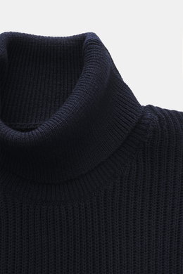 Close-up front view of C.P. Company Turtleneck sweater navy, knit from virgin wool and microfiber, soft feel, medium-fine knit, rib stitch, slim fit, close turtleneck, zippered upper arm pocket, lens detail, flexible rib cuffs.