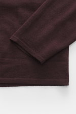 Close-up top-down view of the sleeve and hem of the Kiefermann Merino Fine Knit Sweater 'Malt' burgundy, pure merino wool, super soft touch, very fine knit pattern, slim fit, high crew neckline, elastic sleeve cuffs.