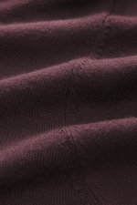 Close-up shot of burgundy fabric showing very fine knit pattern and texture of the Kiefermann Merino Fine Knit Sweater 'Malt' burgundy, made of pure merino wool with a super soft touch, slim fit, high crew neckline, and elastic sleeve cuffs.