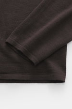 Close-up top-down view of the sleeve and lower body of the Kiefermann Merino Fine Knit Sweater 'Malt' dark brown, featuring pure merino wool, super soft touch, very fine knit pattern, slim fit, high crew neckline, and elastic sleeve cuffs.