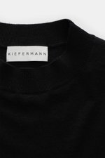 Close-up front view of the Kiefermann Merino fine knit sweater 'Malt' black, showing pure merino wool, super soft touch, very fine knit pattern, slim fit, high crew neckline, and elastic sleeve cuffs.