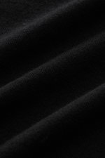Close-up front-angle view of black fabric showing very fine knit pattern of the Kiefermann Merino fine knit sweater 'Malt' black, made of pure merino wool with a super soft touch, slim fit, high crew neckline, and elastic sleeve cuffs.