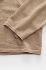 Close-up image from above showing the sleeve and hem of the Kiefermann Merino Fine Knit Sweater 'Malt' light brown, featuring pure merino wool, super soft touch, very fine knit pattern, slim fit, high crew neckline, and elastic sleeve cuffs.