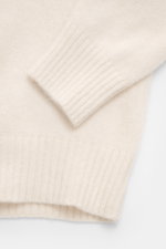 Nahaufnahme des Filippo de Laurentiis Rollkragenpullovers creme, fotografiert von oben, zeigt mittelfeines Strickbild, flexibles Rippbündchen, Slim Fit, anliegenden Rollkragen, Mix aus Cashmere, Seide und Microfaser mit sehr weichem, voluminösem Griff.