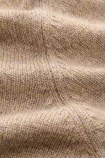 Nahaufnahme des feinen Strickbilds und der weichen Oberfläche des beige melierten Filippo de Laurentiis Cashmere Rollkragenpullovers, fotografiert aus seitlicher Perspektive.