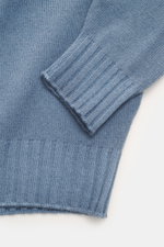 Nahaufnahme des Filippo de Laurentiis Rollkragenpullovers rauchblau, fotografiert von oben mit Fokus auf feines Strickbild, Rippstrick-Rollkragen und flexible Rippbündchen aus Super 120'S Wolle und Cashmere.
