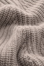 Nahaufnahme des Allude Mock Neck Pullovers beige meliert, fotografiert aus nächster Nähe, zeigt weichen Griff, mittelgrobes Strickbild mit Patent-Strickmuster, Mix aus Wolle und Cashmere, Regular Fit, Stehkragen, Raglan-Ärmel und komfortable Rippbündchen.