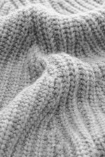 Nahaufnahme des Allude Mock Neck Pullover grau meliert aus Wolle und Cashmere mit weichem Griff, mittelgroßem Patent-Strickmuster, Stehkragen, Raglan-Ärmeln, Regular Fit und Rippbündchen, Detailfoto der Struktur.