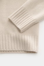 Nahaufnahme des Bruno Manetti Cashmere Rollkragenpullovers sand, fotografiert von oben auf Ärmel und Saum mit weichem, mittelfeinem Strickbild.