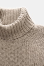 Nahaufnahme des Rollkragens in seitlicher Perspektive eines FTC Cashmere Rollkragenpullovers beige meliert aus nachhaltigem, weichem, mittelfeinem Strick.