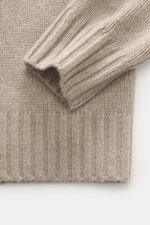 Nahaufnahme des FTC Cashmere Rollkragenpullovers beige meliert, fotografiert von schräg oben, zeigt weiche, mittelfeine Strickstruktur, Rollkragen und Rippbündchen.