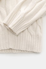 Nahaufnahme des Moorer Rollkragenpullovers 'Gordon' creme, fotografiert von oben, mit schwerem Zopfmuster aus Woll-Cashmere-Mix, weichem Griff und flexiblen Rippbündchen.